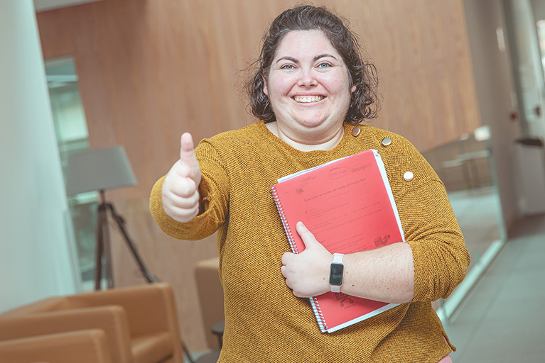 Una chica sonriente haciendo el gesto de pulgar arriba.